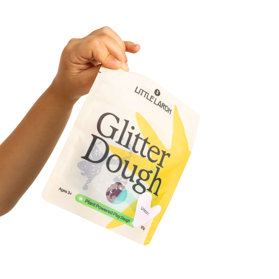 Hand holding a package of Little Larch Glitter Dough on a white background