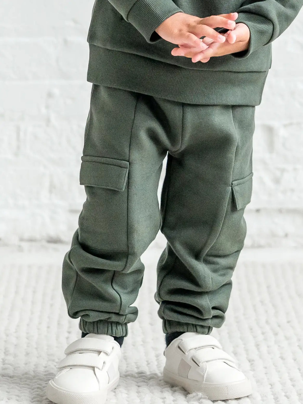 Person wearing a green tracksuit with cargo pockets on a white background